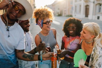Young tourists toasting with bottles on a city street during summer vacation