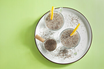 Top view of two glasses of healthy drink chia water with slices of lemon on green background, great for hydration, digestion and detox, flat lay with copy space on the left side