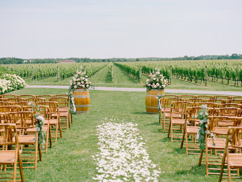 Beautiful vineyard wedding setup featuring flower arrangements and wooden chairs under a clear sky