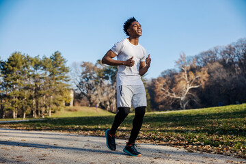 Full length of smiling healthy fit sportsman jogging in nature.