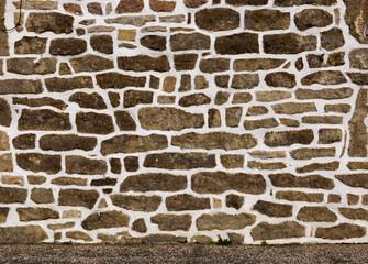 Rustic stone wall with irregular brown rocks and white mortar, creating a textured architectural background.