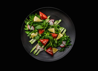 salad of beautifully arranged vegetables radishes cucumbers parsley greens on a white plate and on a black background
