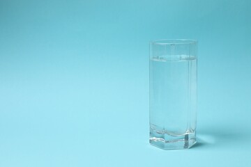 Transparent glass with water on blue background. Drinking clear water in the morning for health