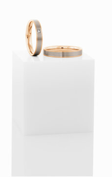 Wedding rings on top of white pedestal.