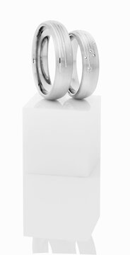 Wedding rings on top of white pedestal.