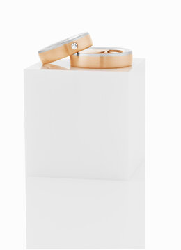 Wedding rings on top of white pedestal.
