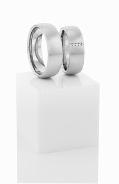 Wedding rings on top of white pedestal.