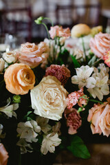 Flower arrangement with soft pastel roses and white blooms at an indoor event setting