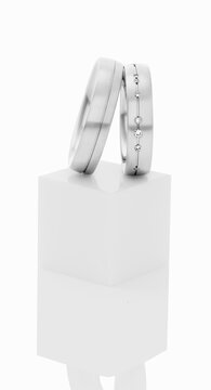 Wedding rings on top of white pedestal.