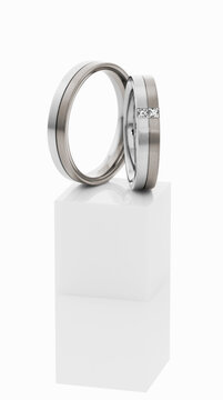 Wedding rings on top of white pedestal.