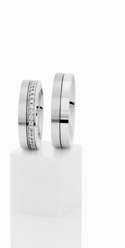 Wedding rings on top of white pedestal.