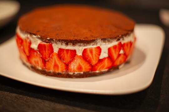 Chocolate topped strawberry cake in a kitchen.