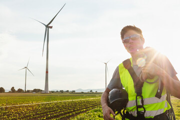 Wind farm technician working in the field near wind mills.