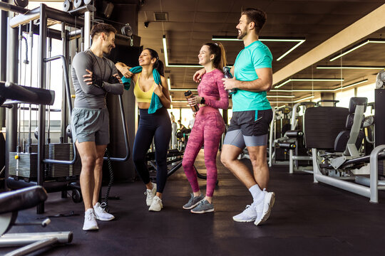 Group of four people met up at the gym and they talk and rest from the training.