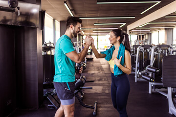 Two fit people high five after good workout in the gym.