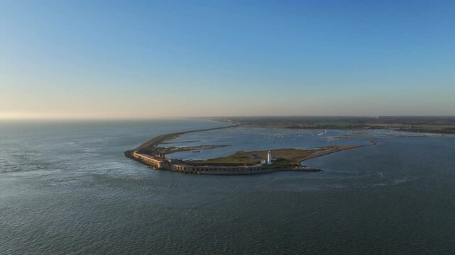 Wide aerial drone shot of Hurst Point Lighthouse and the historic Hurst Castle on a long peninsula sticking into the Solent south of Lymington, England