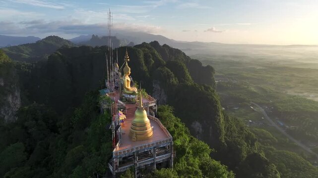 Dynamic close-up drone footage of the golden Buddha statue and temple atop the Tiger Cave Temple mountain in Krabi, Thailand