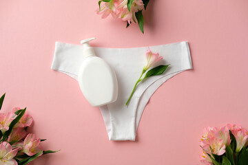 The concept of feminine hygiene. Women's panties, intimate hygiene gel and delicate flowers on pink background