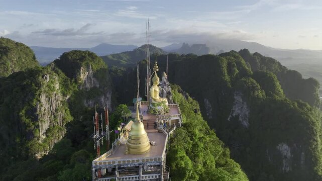 Aerial HDR drone video of the Tiger Cave Temple (Wat Tham Suea) gold Buddha atop the mountain behind the complex in Krabi, Thailand 