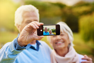 Senior, happy couple or love with phone screen for selfie, picture or photography at outdoor park. Hand, portrait or elderly lover with camera or smile for capture moment or memory together in nature
