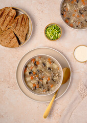 Food photography of mushroom soup with barley and vegetables, carrots; potatoes, spring onion, cream, toasted bread, vegetarian healthy food