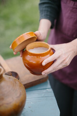 Hands Opening a Ceramic Pot Outdoors for Food Storage