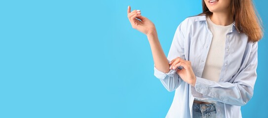 Young woman rolling up her sleeve on  light blue background with space for text