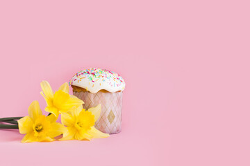 Traditional russian Easter ortodox cake with daffodil flower and colorful eggs on light pink background. Kulic, Kulich, Paska homemade bread with glaze. Spring christian holiday. Festive celebration