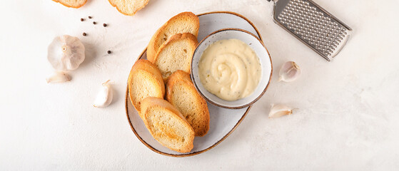 Plate of tasty croutons and bowl with sauce on white background
