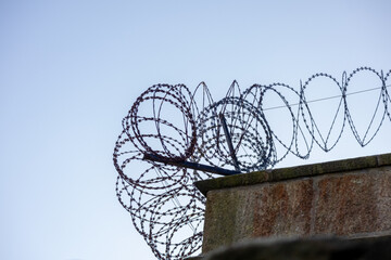 Concrete wall with barbed wire, view from below against the sky. The top edge of fence. Scotland