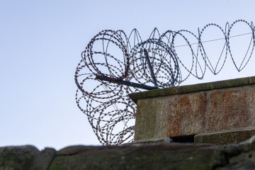 Concrete wall with barbed wire, view from below against the sky. The top edge of fence. Scotland