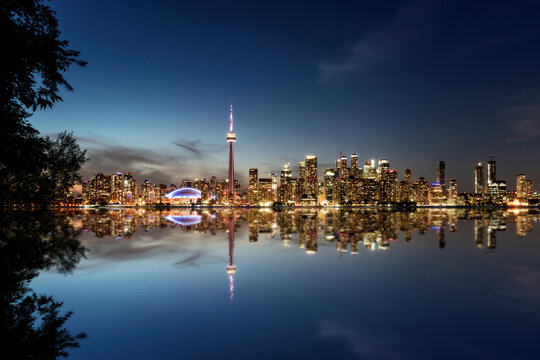 Toronto skyline reflecting at twilight over lake ontario