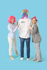 Business women pointing at paper fish on their colleague's back against blue background. April Fools' Day celebration