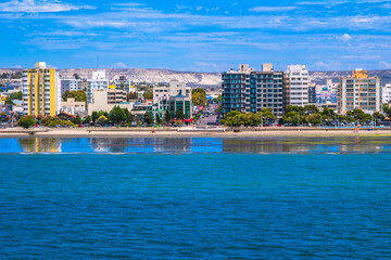 Fototapeta premium Puerto Madryn, Argentina - December 17, 2024: Hi-rise building reflections are mirrored along the waterfront.