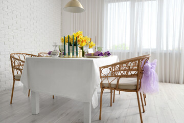 Beautiful table setting with daffodils and candles for wedding celebration in room