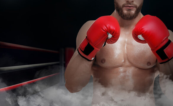 Boxer wearing red gloves on boxing ring in smoke, closeup. Space for text