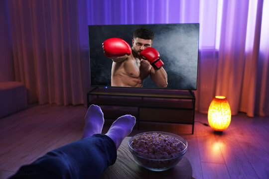 Man watching boxing fight on TV set at home, closeup