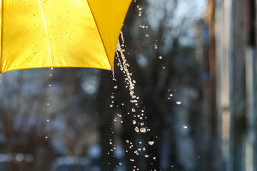 Open yellow umbrella under pouring rain outdoors, closeup