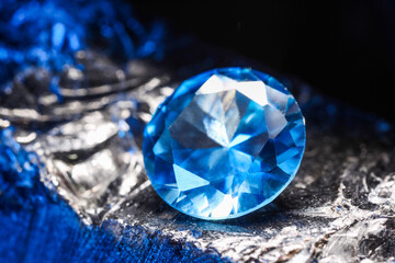 Beautiful shiny light blue gemstone on stone against black background, closeup