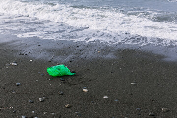 Obraz premium plastic bag on the seashore, sea wave. Ecological problem, pollution of the planet and ocean. volunteer programs to clean up water bodies