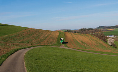 Naklejka premium Scenic countryside landscape with rolling hills and winding road under clear blue sky