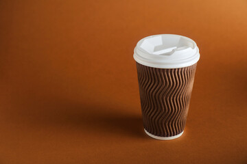 One paper cup on brown background. Mockup for design
