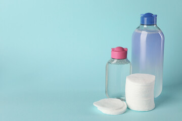 Clean cotton pads and micellar water on light blue background. Space for text