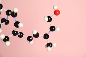 Molecule of retinol (vitamin A) on pink background, closeup. Chemical model