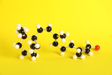 Molecule of retinol (vitamin A) on yellow background. Chemical model