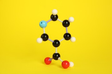 Molecule of niacin (vitamin B3) on yellow background. Chemical model