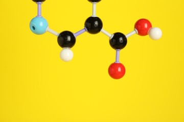 Molecule of niacin (vitamin B3) on yellow background, closeup and space for text. Chemical model