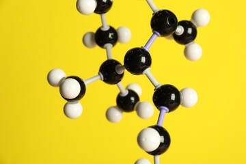 Molecule of retinol (vitamin A) on yellow background, closeup. Chemical model