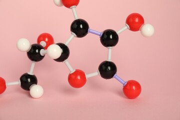 Molecule of vitamin C on pink background, closeup. Chemical model