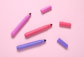 Many colorful markers on pink background, flat lay